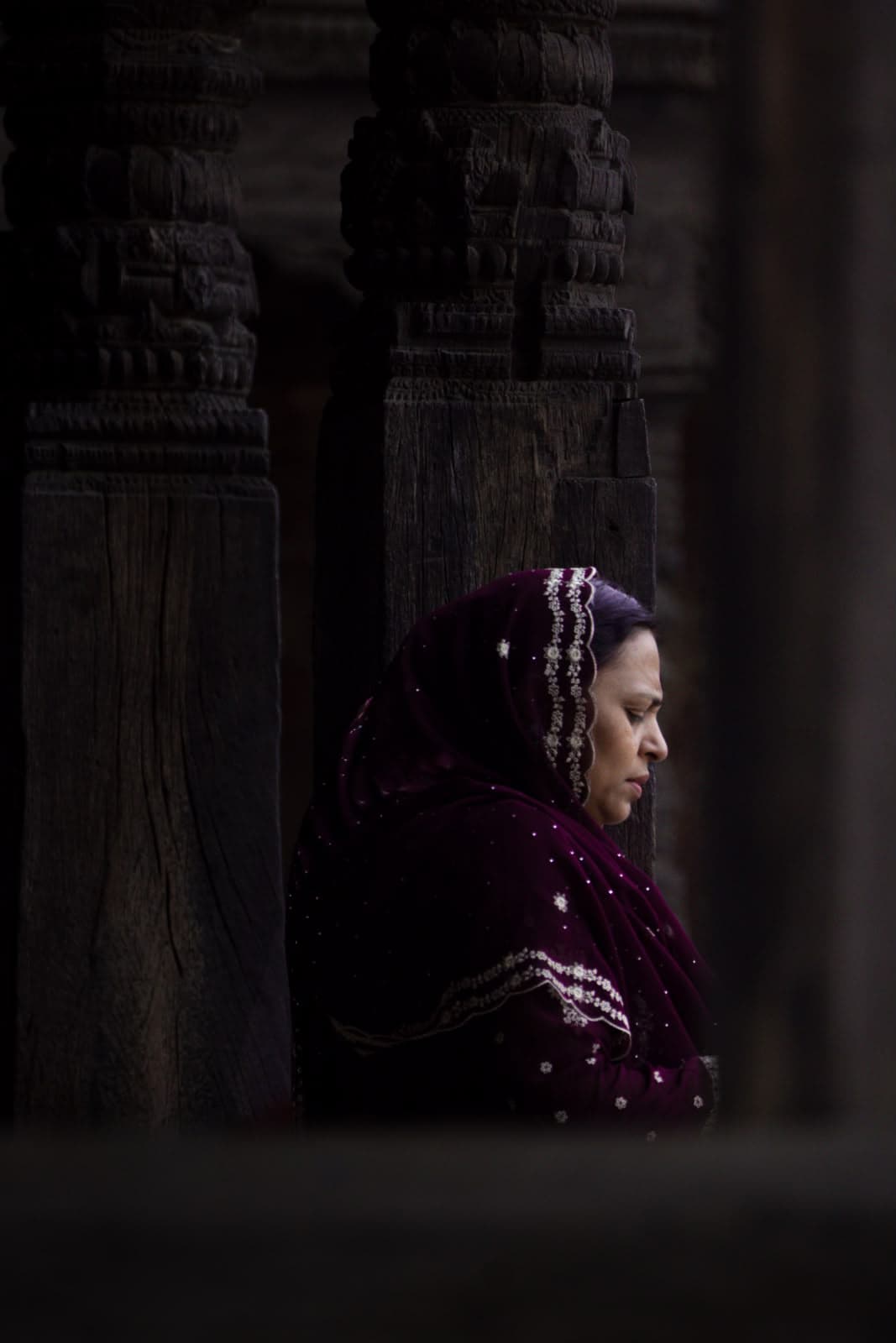 A woman in a maroon shawl, in shadow
