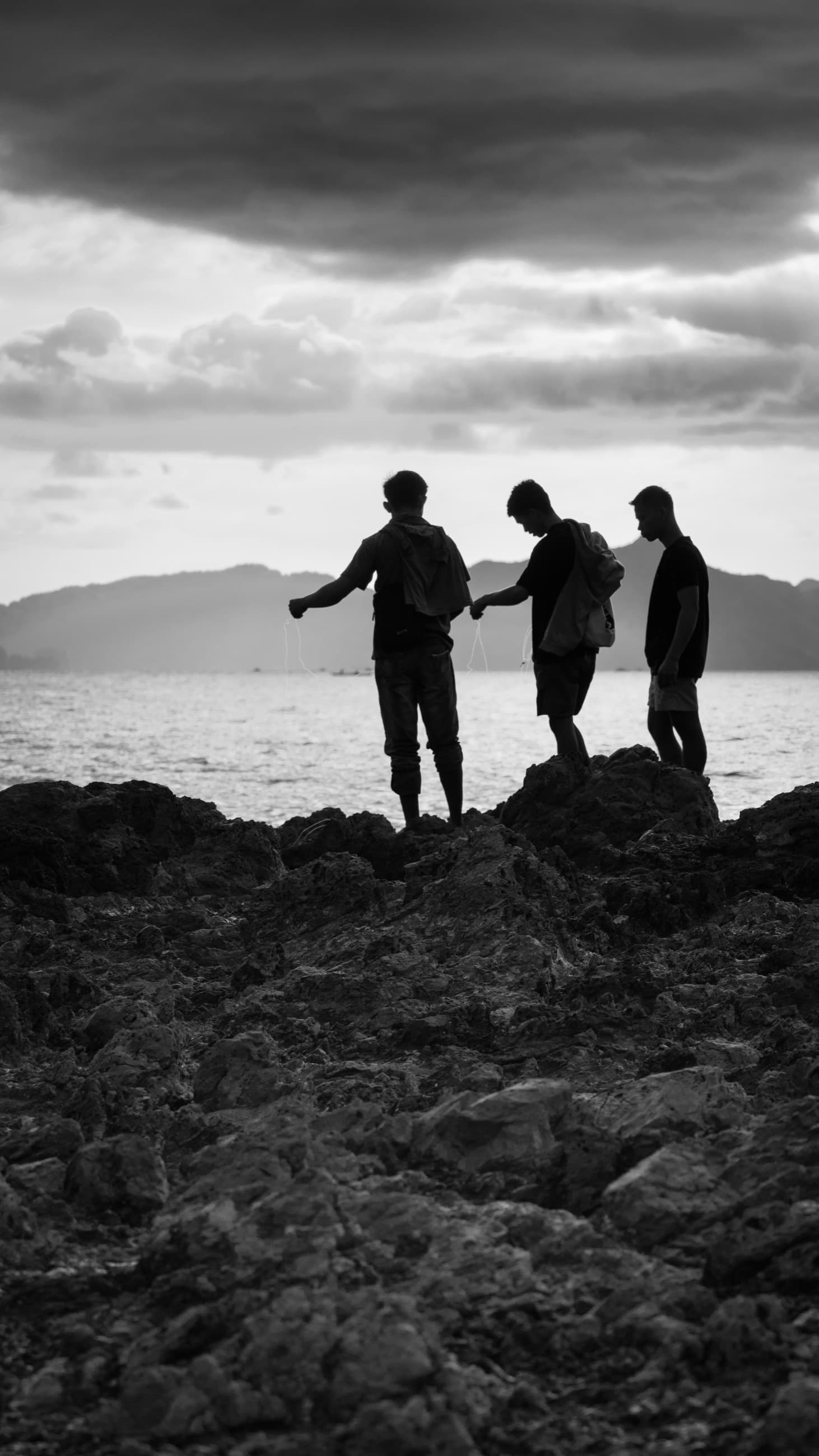 Three figures on a rocky shore, storm sky